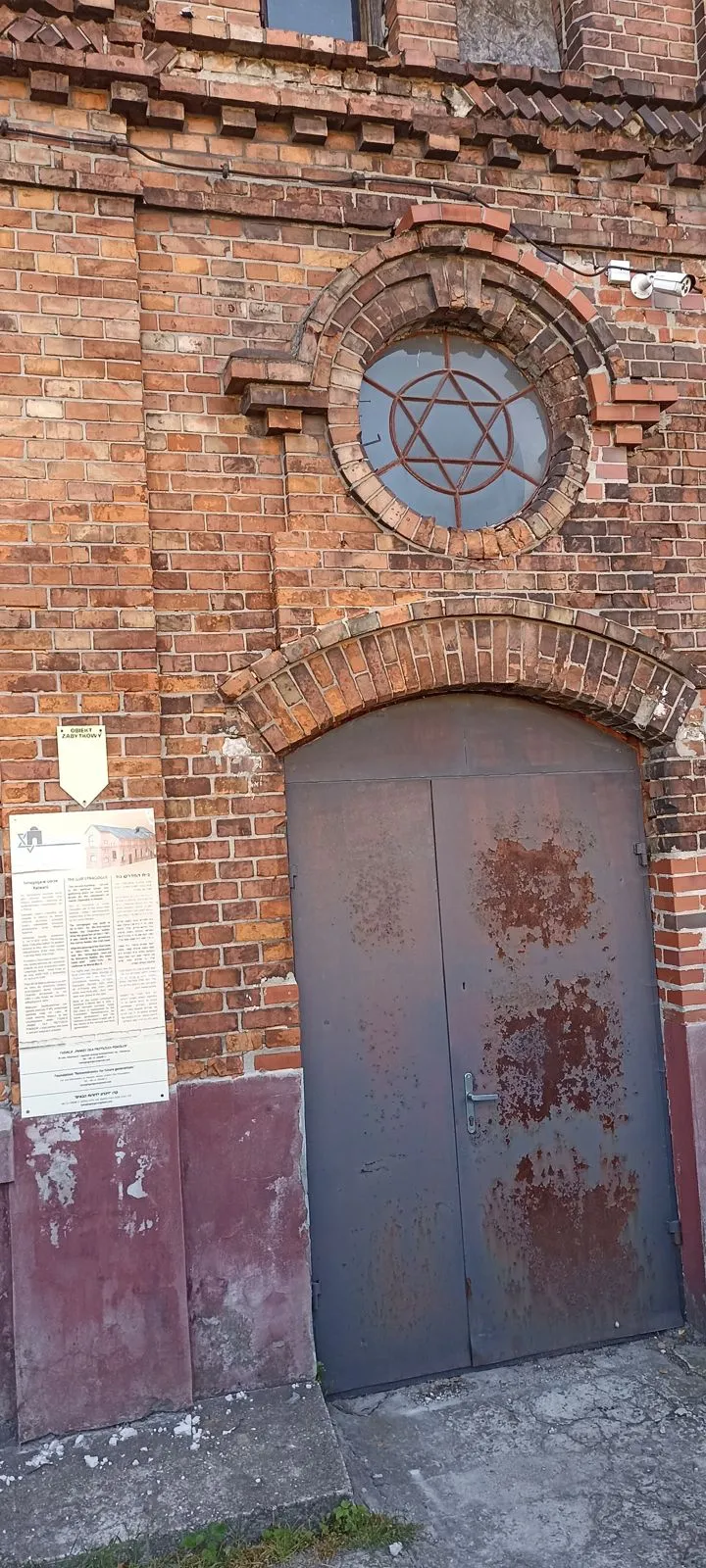 Okrągłe okno z gwiazdą Dawida nad drzwiami ceglanego domu modlitwy