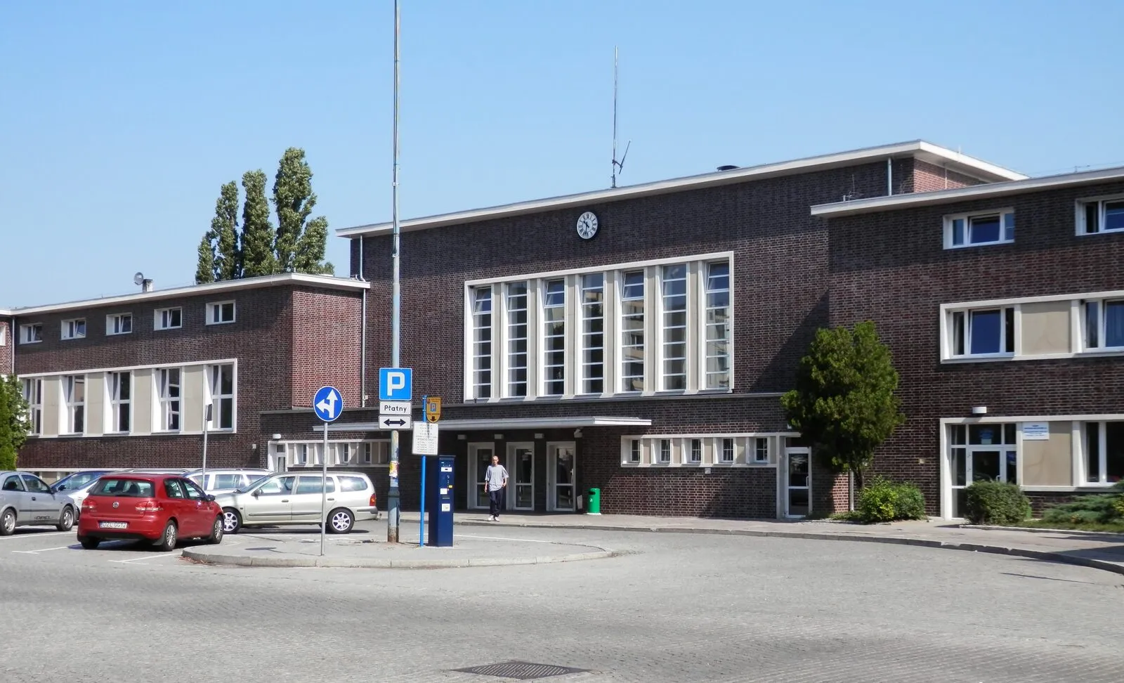 Modernistyczny dworzec kolejowy w Głogowie z klinkierową elewacją i wysokimi oknami hali.