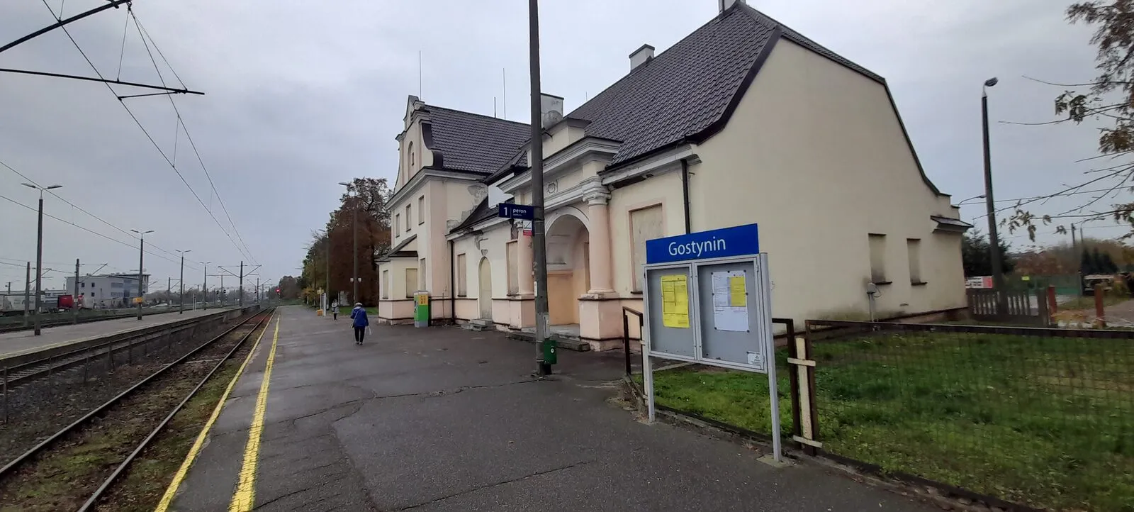 Dworzec kolejowy w Gostyninie widziany od strony peronu, z tablicą stacyjną z nazwą miasta.