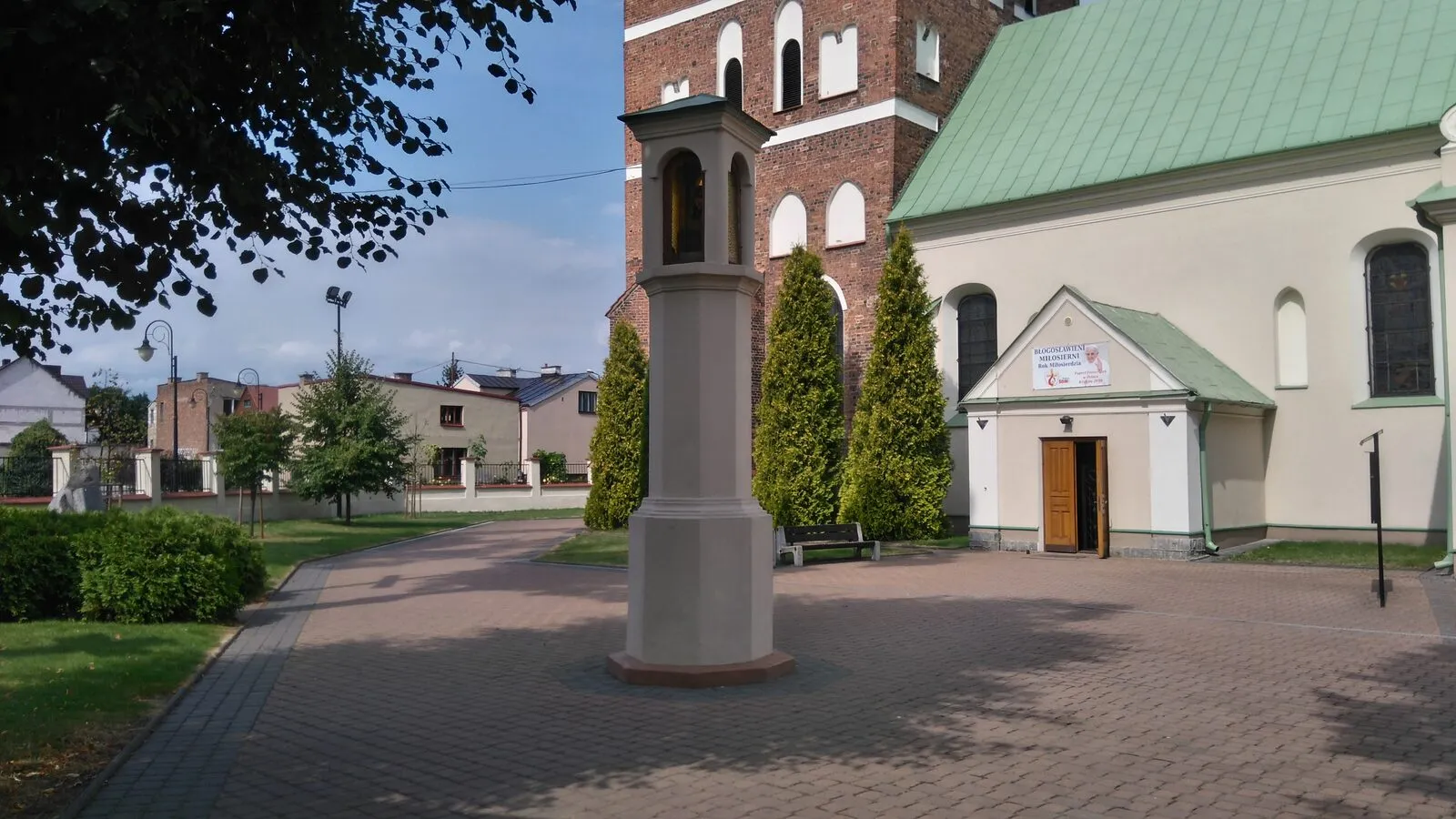 Gotycka wieża i bryła kościoła farnego śś. Wita, Modesta i Krescencji w Sierpcu z placem przed nim.