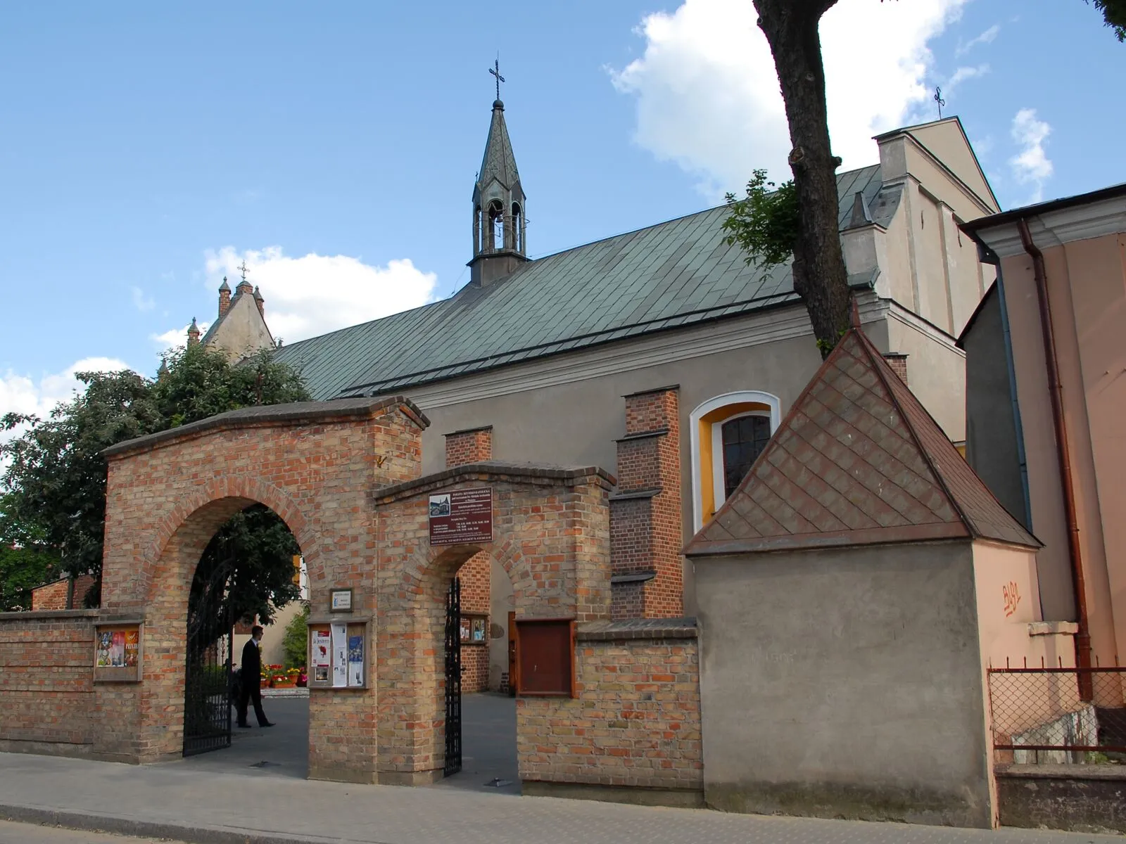 Kościół św. Michała Archanioła w Płońsku od strony ulicy Płockiej: otynkowana bryła z uskokowym szczytem, obok zabudowania dawnego klasztoru.