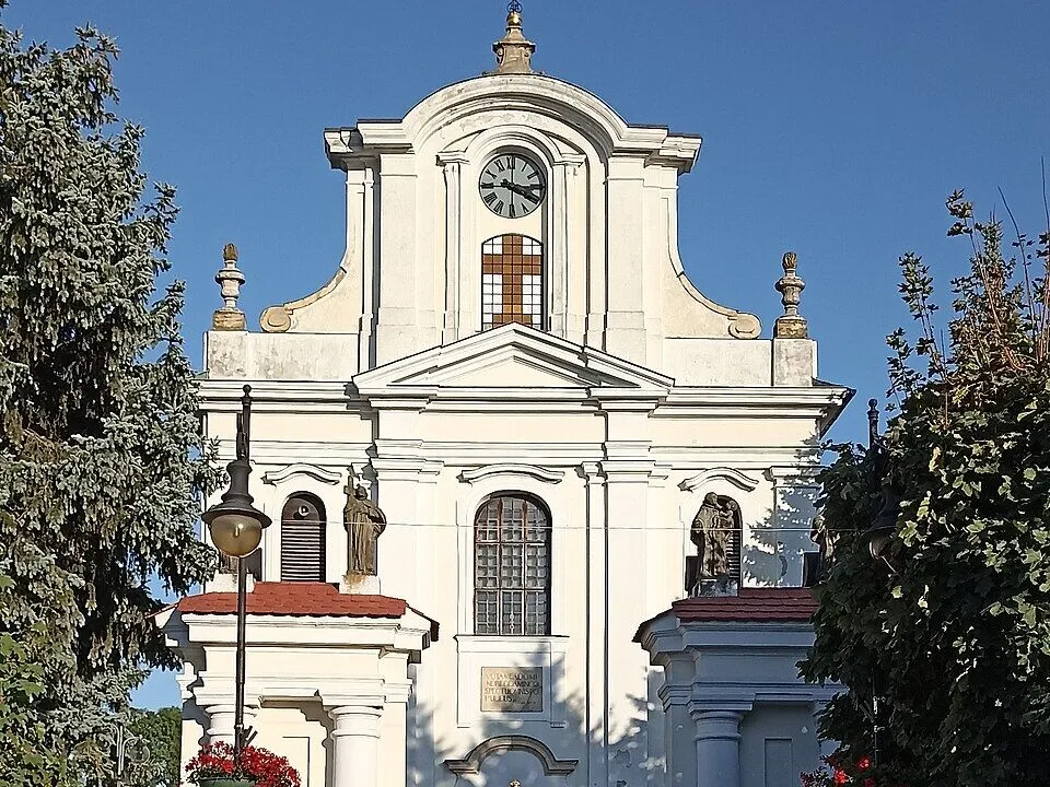 Barokowa fasada kościoła Niepokalanego Poczęcia NMP w Górze Kalwarii z zegarem i falistym szczytem