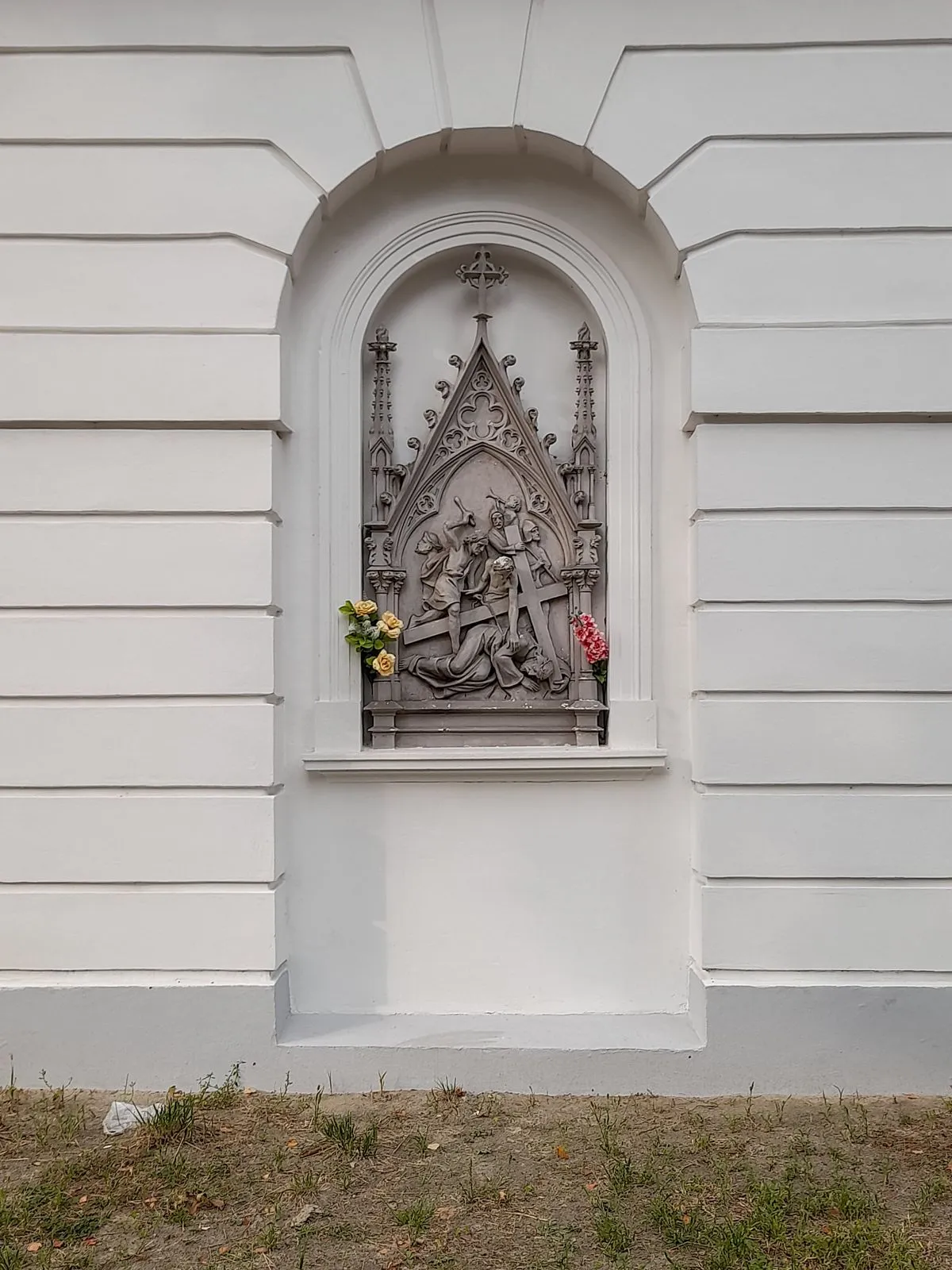 Płaskorzeźba ze stacją Męki Pańskiej wmurowana w ścianę dzwonnicy.