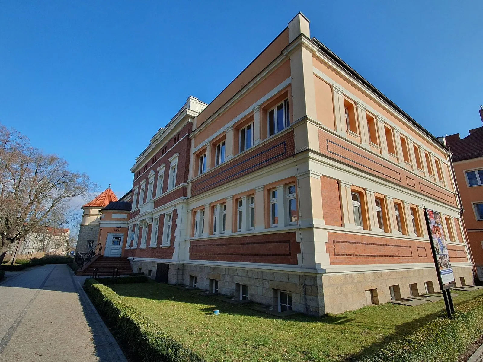 Elewacja łaźni obłożona cegłą i ciosami piaskowca, na kamiennym cokole