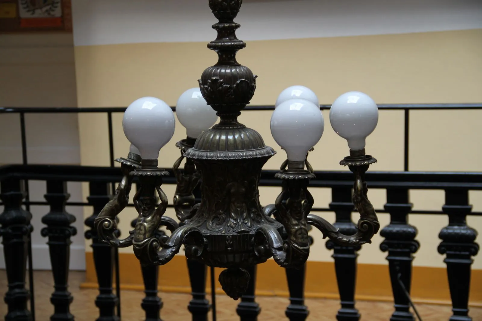 Ozdobny żyrandol nad schodami z rzeźbioną balustradą.