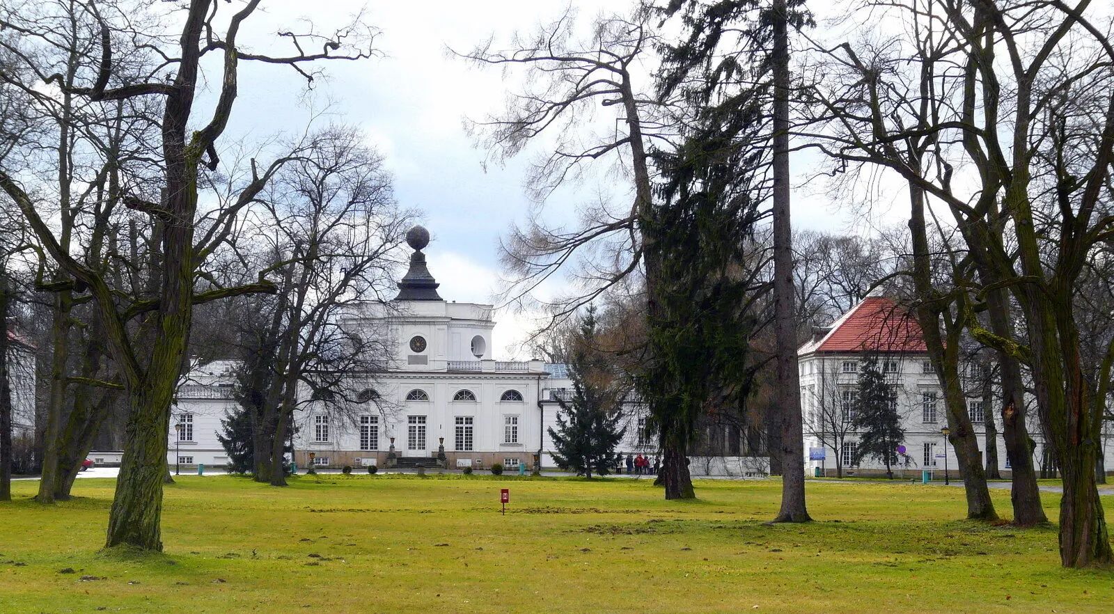 Klasycystyczny pałac w Jabłonnie od strony parku, z centralną rotundą zwieńczoną kopułą, między bezlistnymi drzewami.
