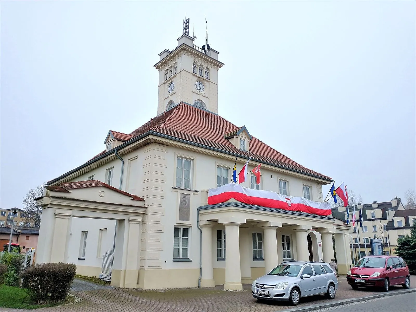 Ratusz z portykiem na kolumnach, wieżyczką z zegarem i bramą przejazdową po boku fasady