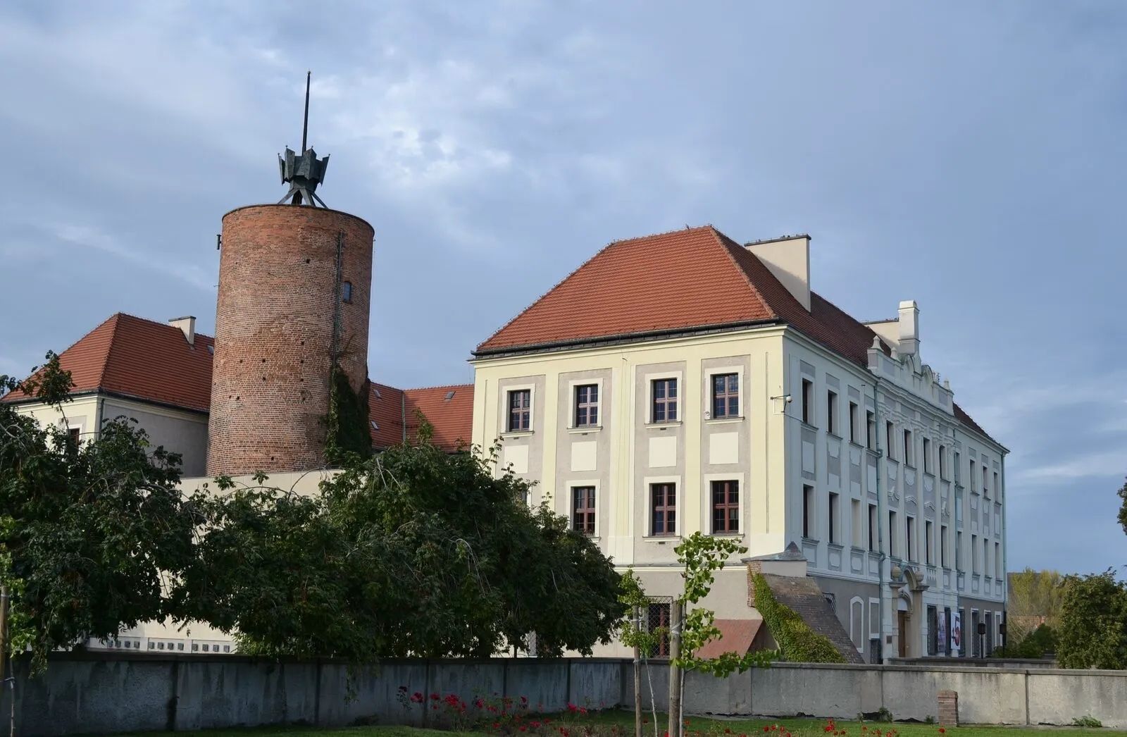 Zamek książąt głogowskich z okrągłą wieżą obronną i barokowym skrzydłem.